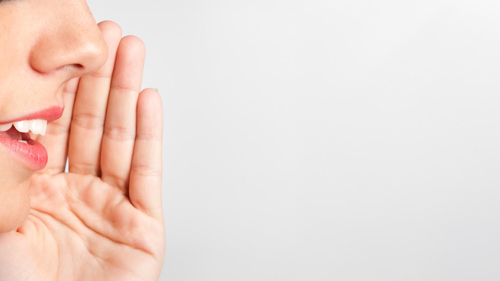 mujer con mano en la boca como susurrando