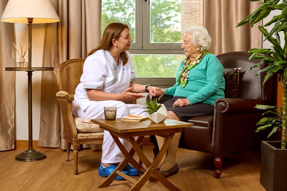 enfermera hablando con anciana en una residencia