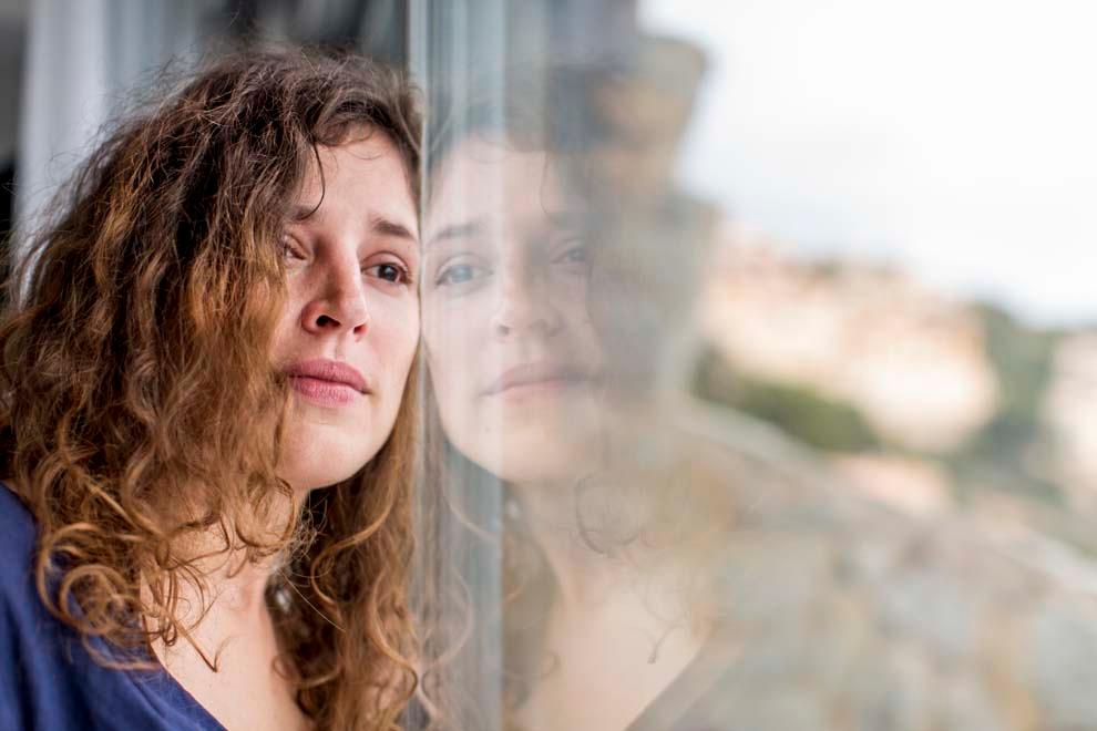 mi madre tiene demencia y no la soporto mujer mirando por la ventana con cara expresiva