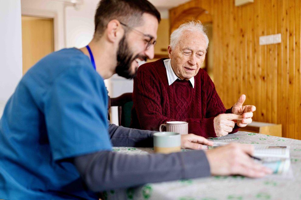 Hombre joven y hombre mayor viendo una revista y tomando una infusión