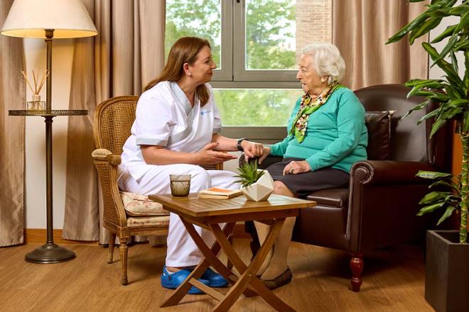 enfermera hablando con anciana en una residencia