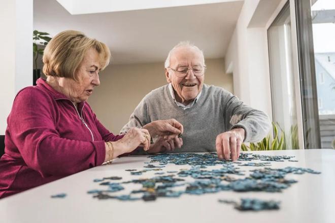 Hombre y mujer mayores haciendo un puzle encima de una mesa