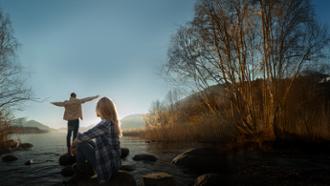 pareja joven viendo amanecer en un río