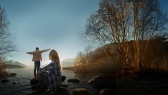 pareja joven viendo amanecer en un río