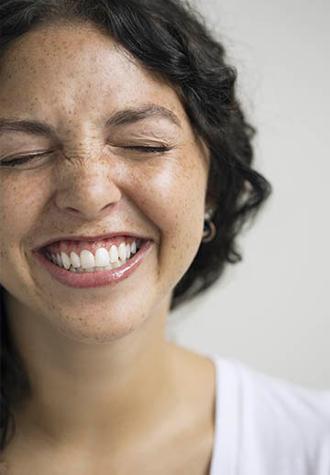 mujer joven sonriendo con los ojos cerrados